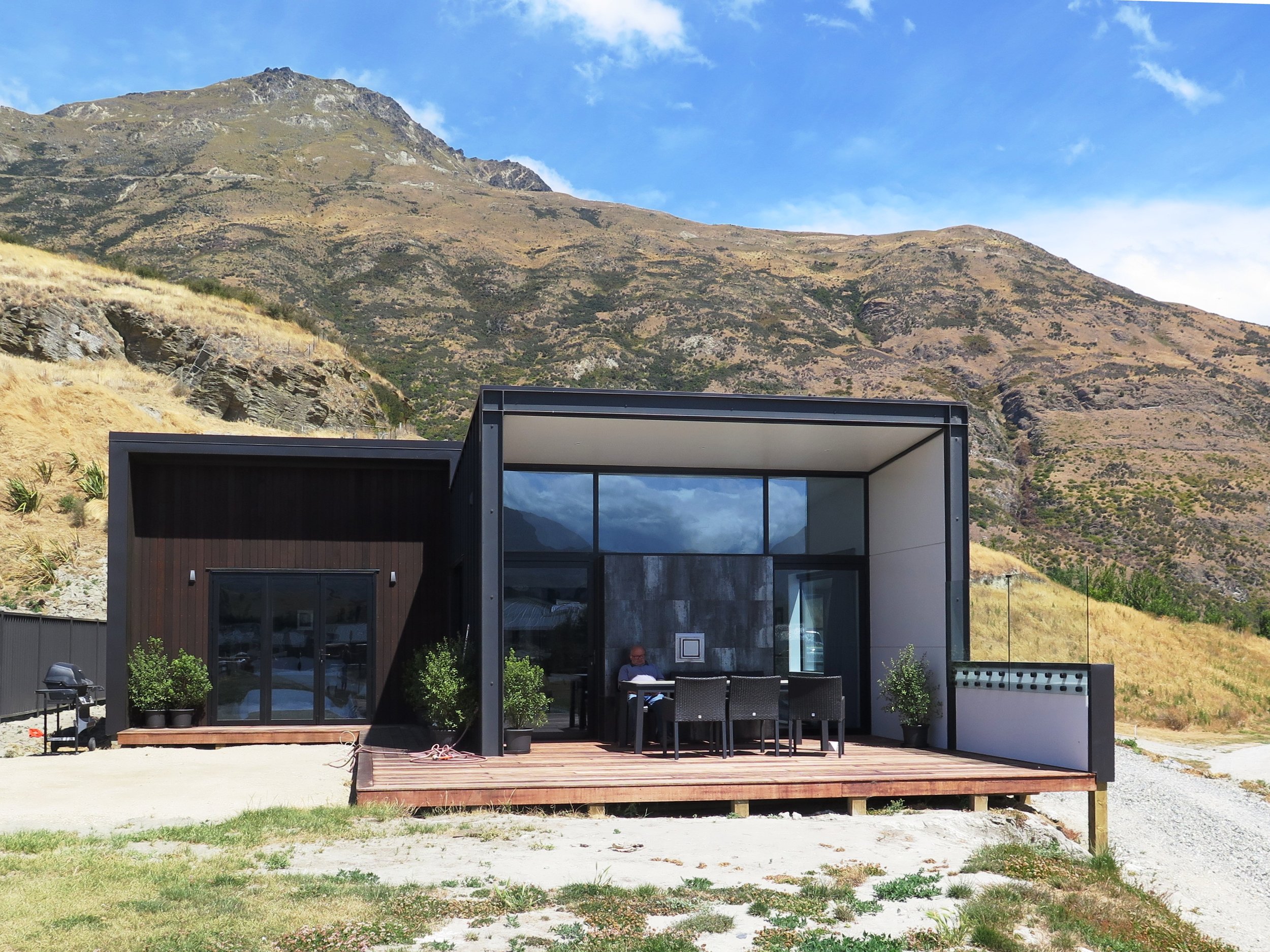 Dark-clad modern house with large glazing in alpine setting